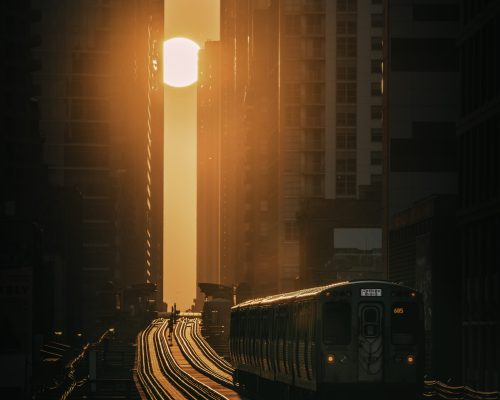 A beautiful shot of a train speeding through the modern city towards the beautiful sunset