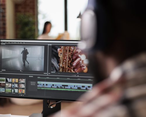 Young freelancer editing footage on software, working to edit video montage with color grading and audio effects. Sound and film production content, making creative movie on computer.